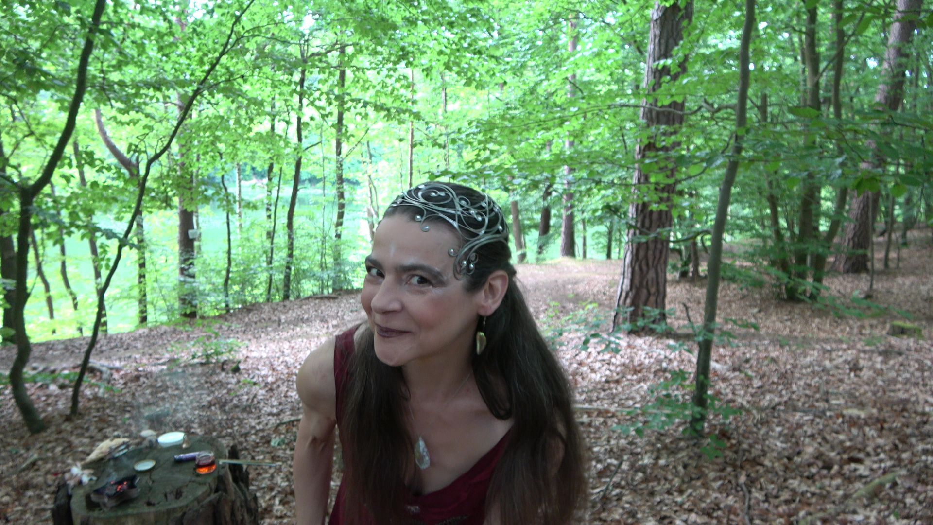 Eine Feuerfee im roten Kleid lacht im Wald 