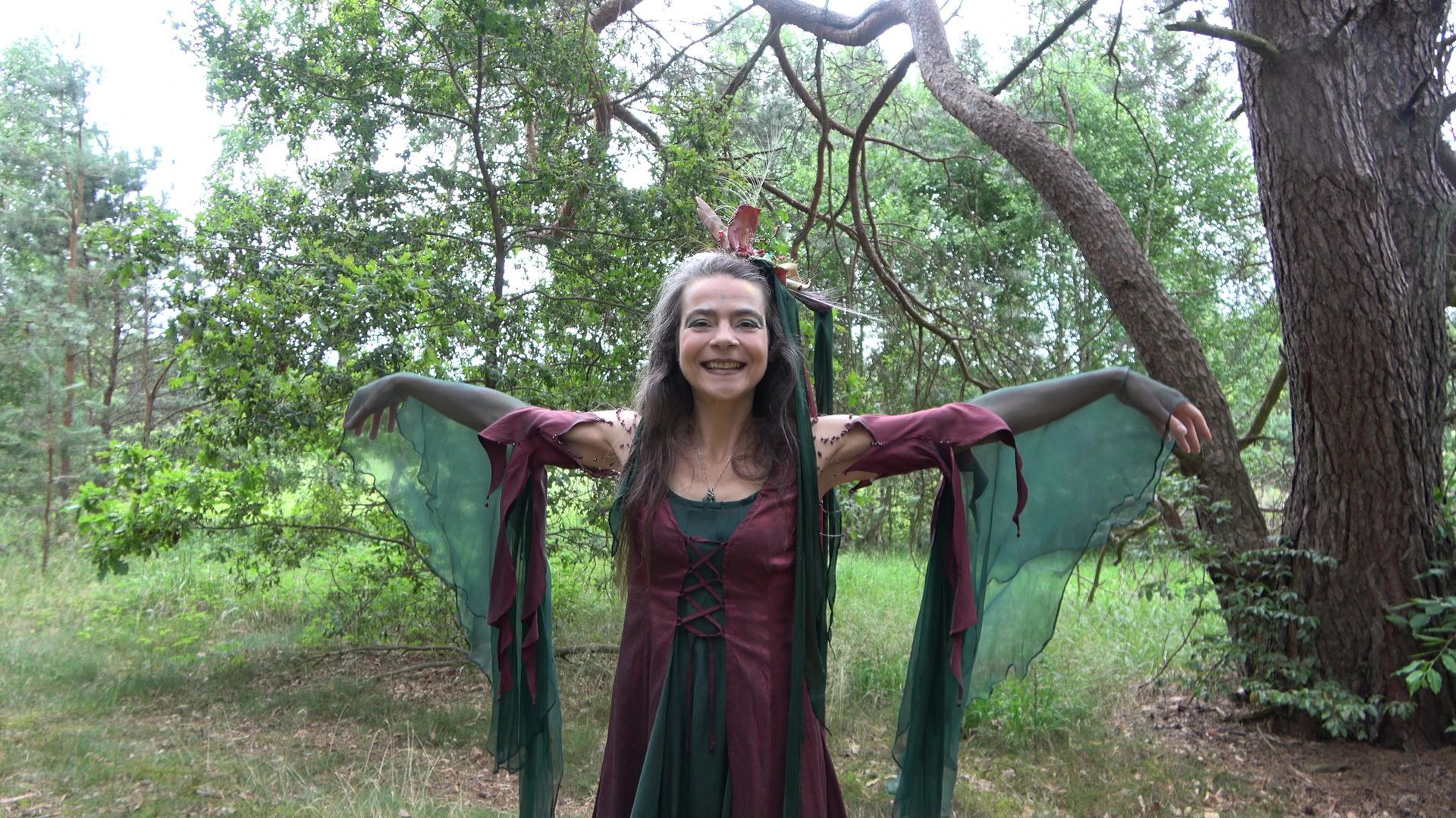 Eine Frau im Feenkostüm tanzt im Wald