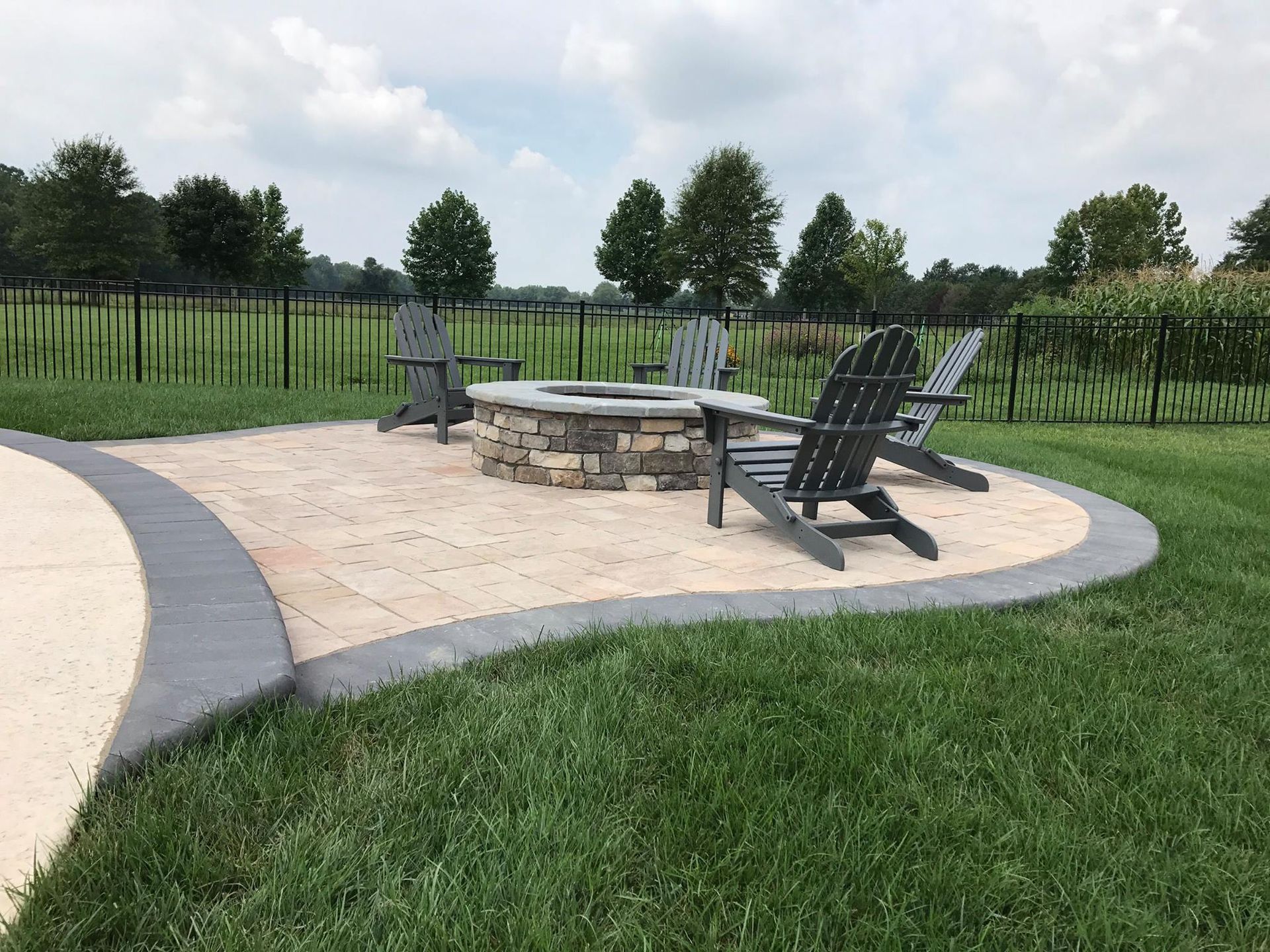 A fire pit with chairs around it in a backyard.