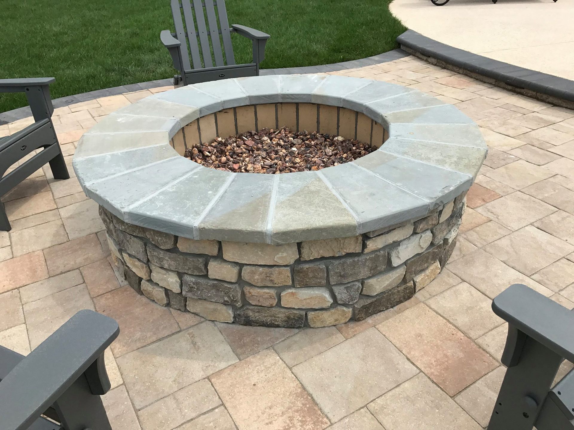 A fire pit on a patio with chairs around it.