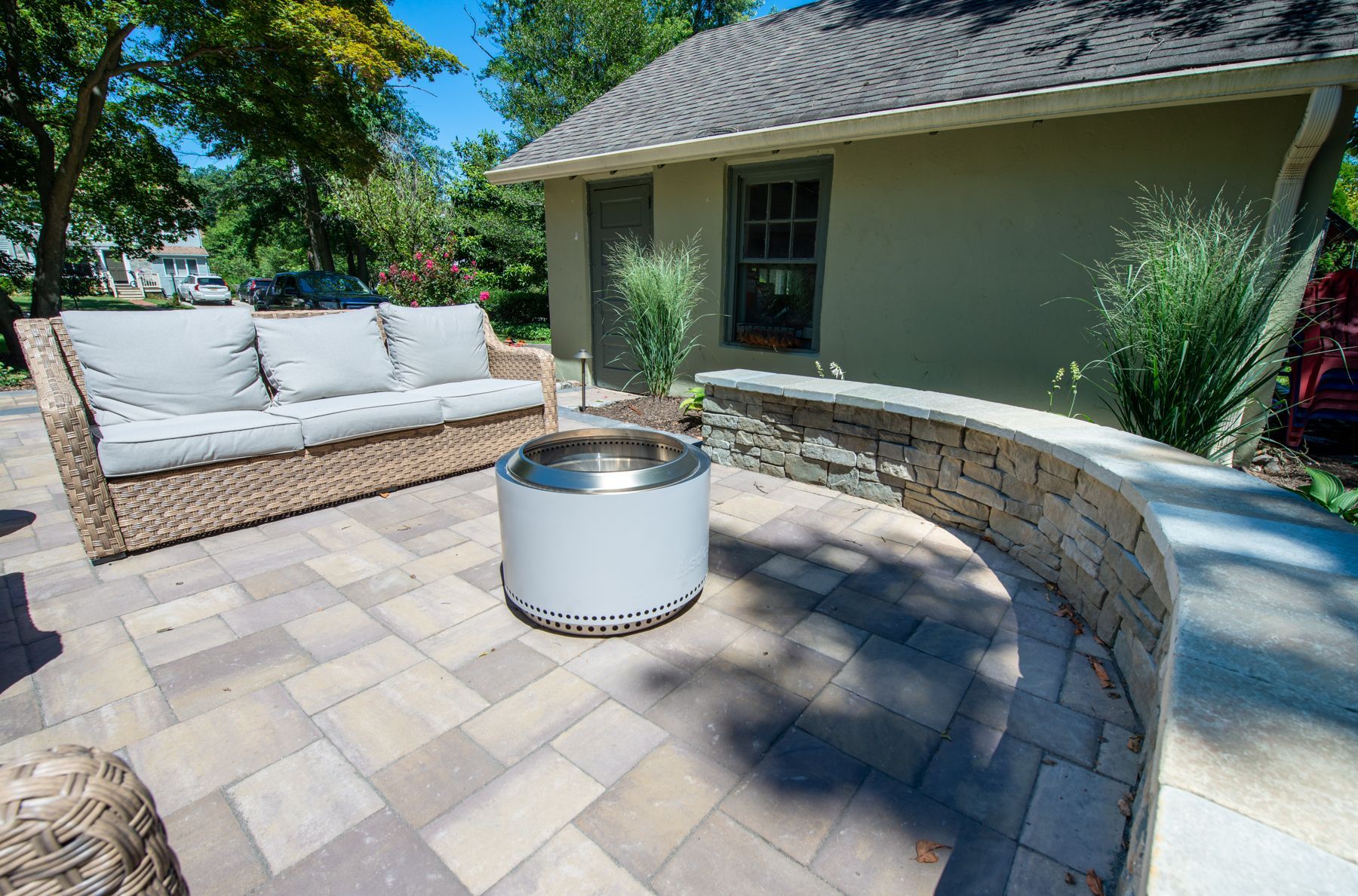 A patio with a couch and a fire pit in front of a house.