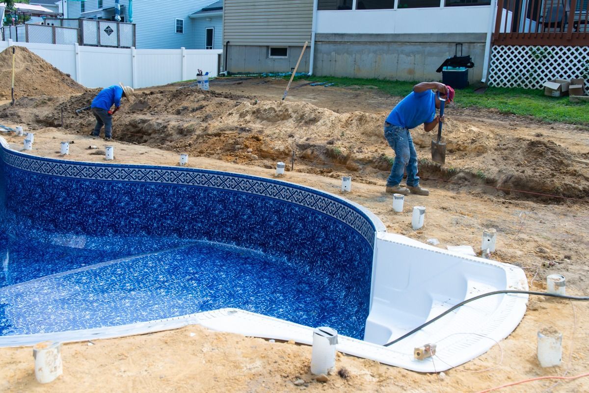 Two men are working on a swimming pool in a backyard.