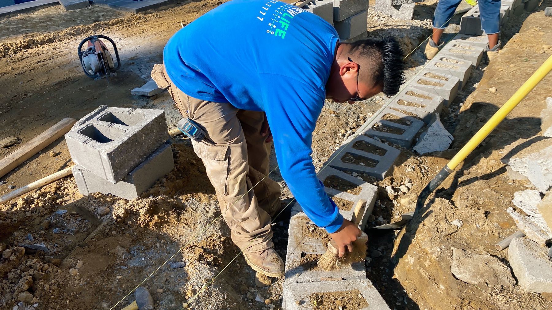 A man in a blue shirt is working on a construction site.