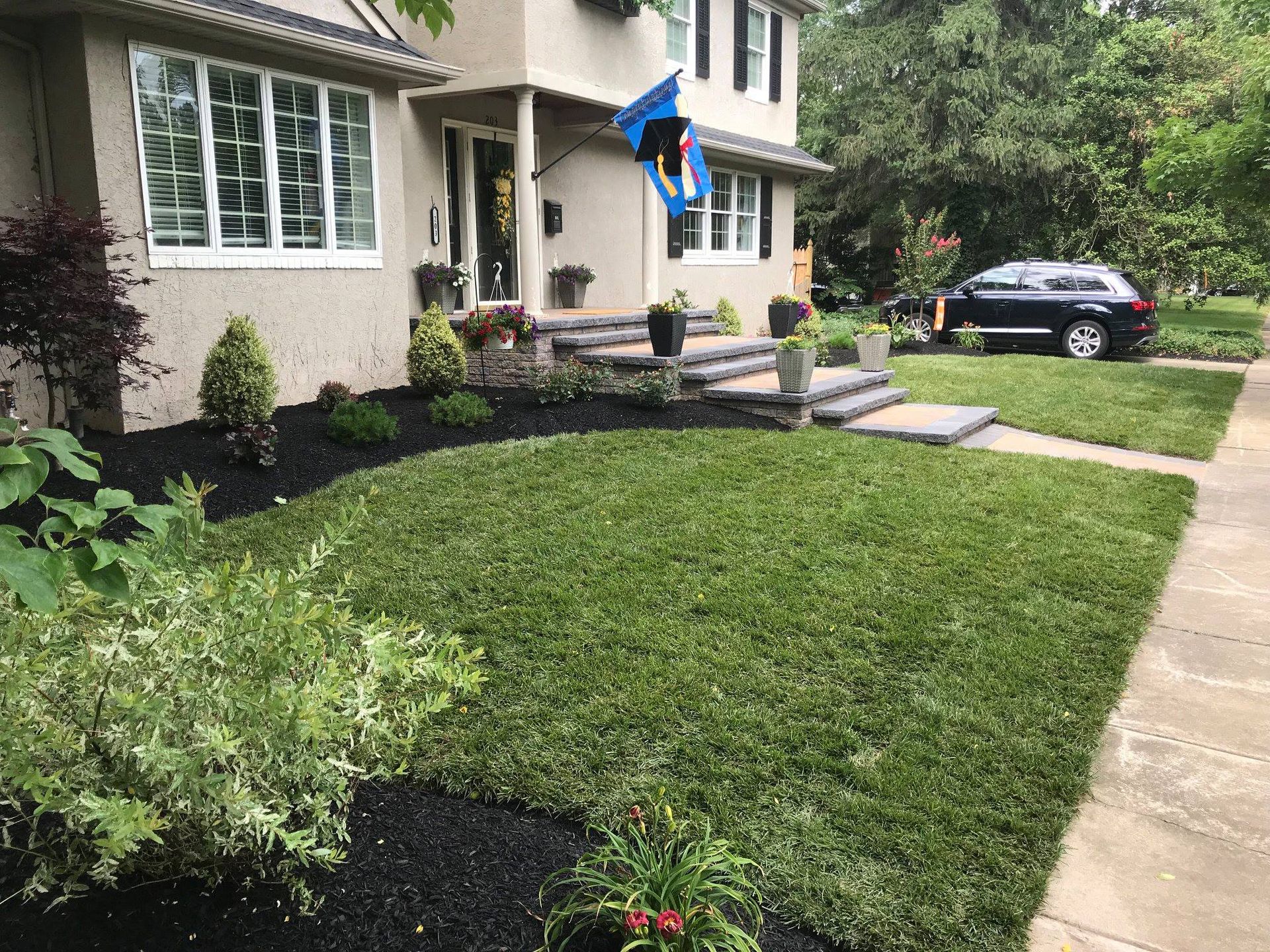 A house with a large lawn and a car parked in front of it.