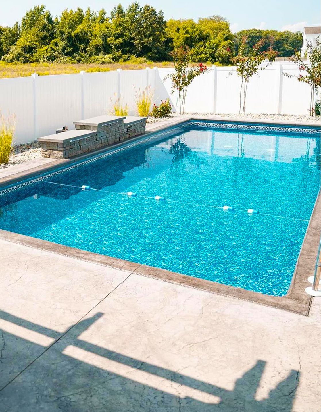 A large swimming pool is surrounded by a white fence.