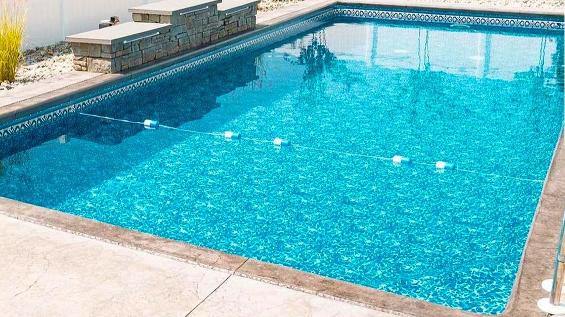 A large swimming pool filled with blue water in a backyard.