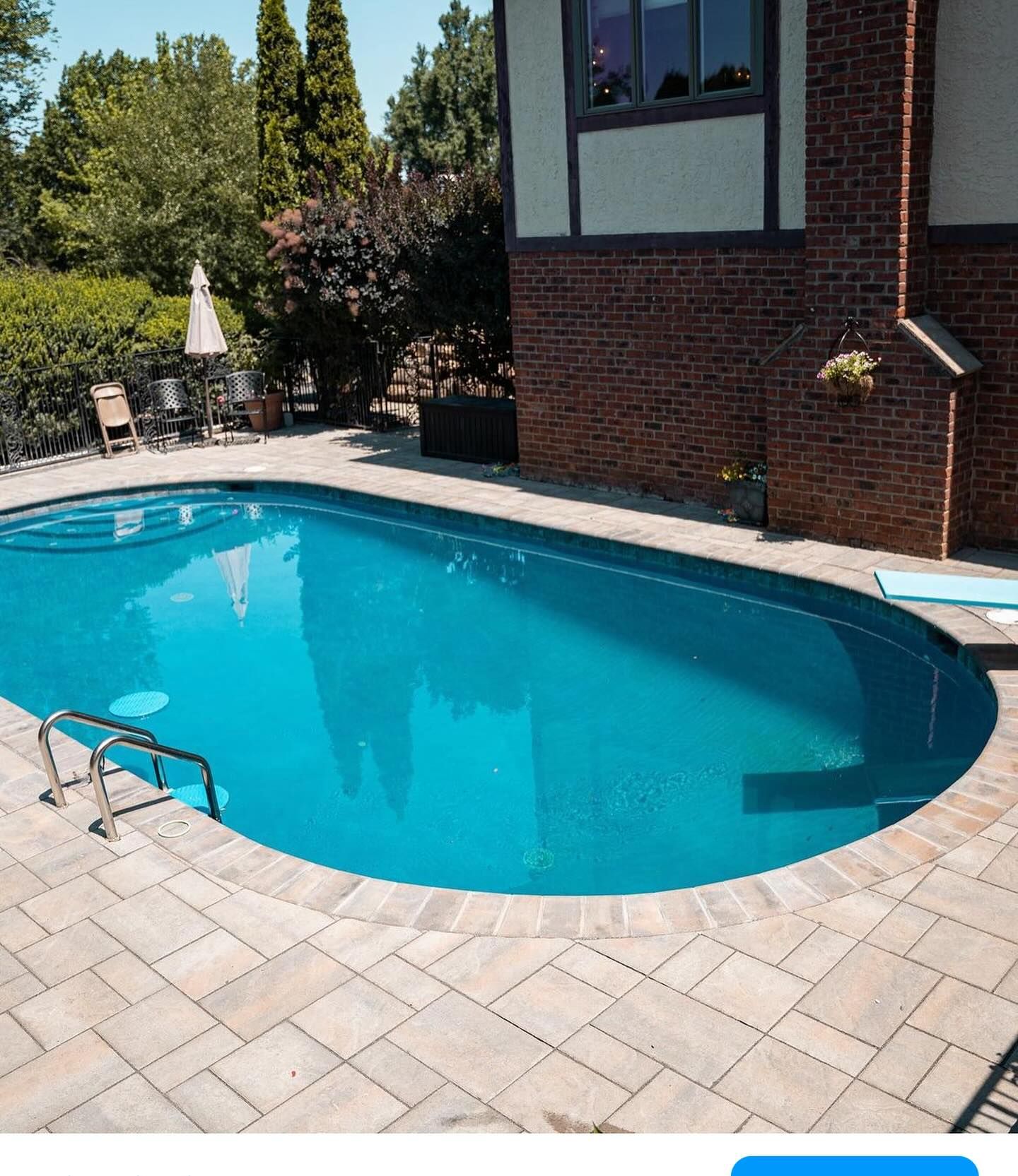 A large oval shaped swimming pool in front of a brick house