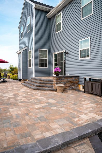 A large blue house with a patio in front of it.