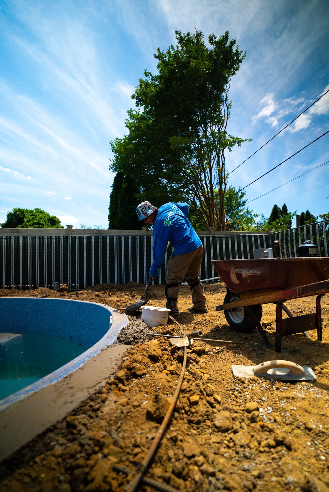 A man is working on a pool next to a wheelbarrow.