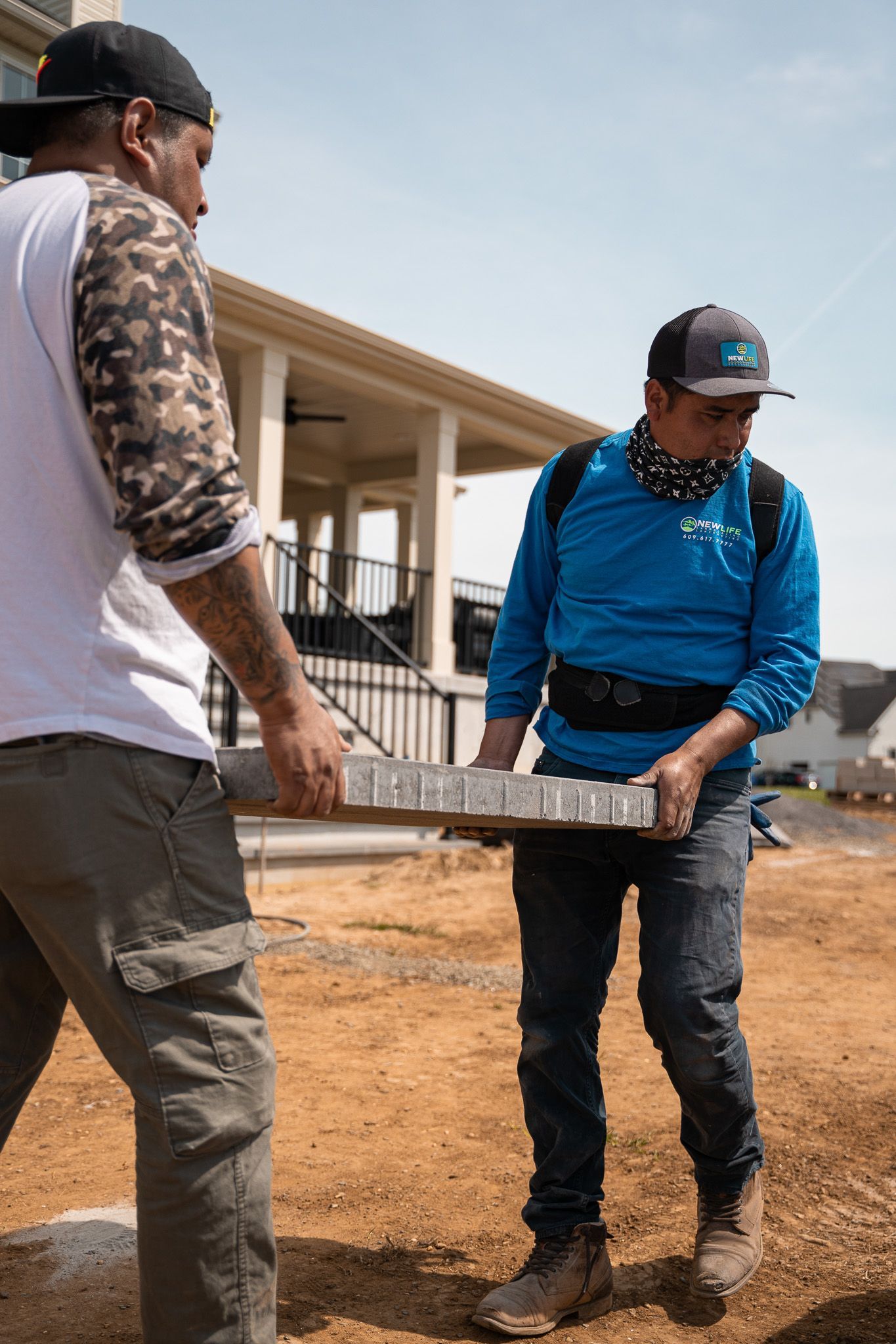 Two men are carrying a large piece of concrete on a construction site.