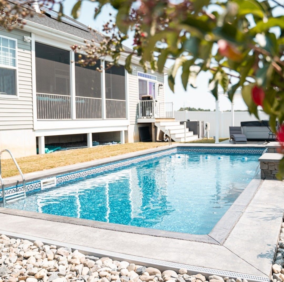 A wooden bench is sitting on a sidewalk next to a grassy field.