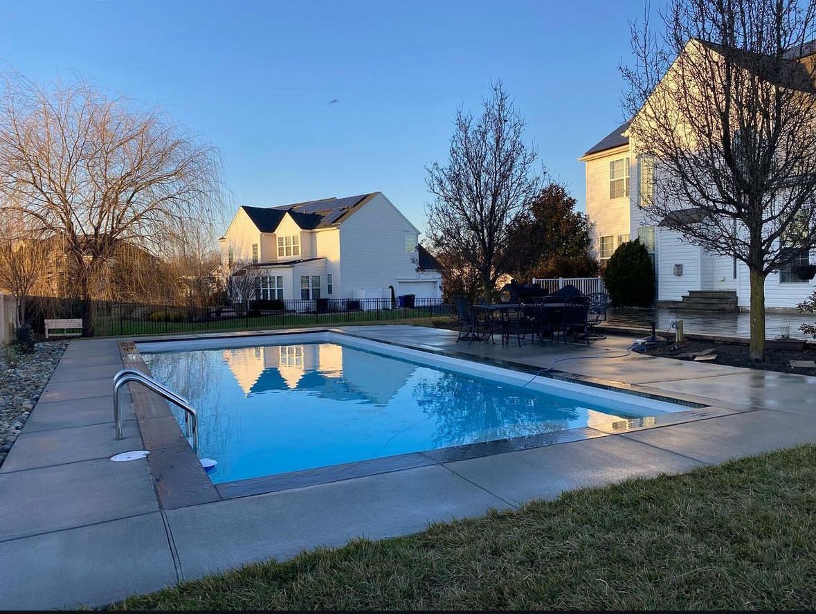 There is a large swimming pool in the backyard of a house.