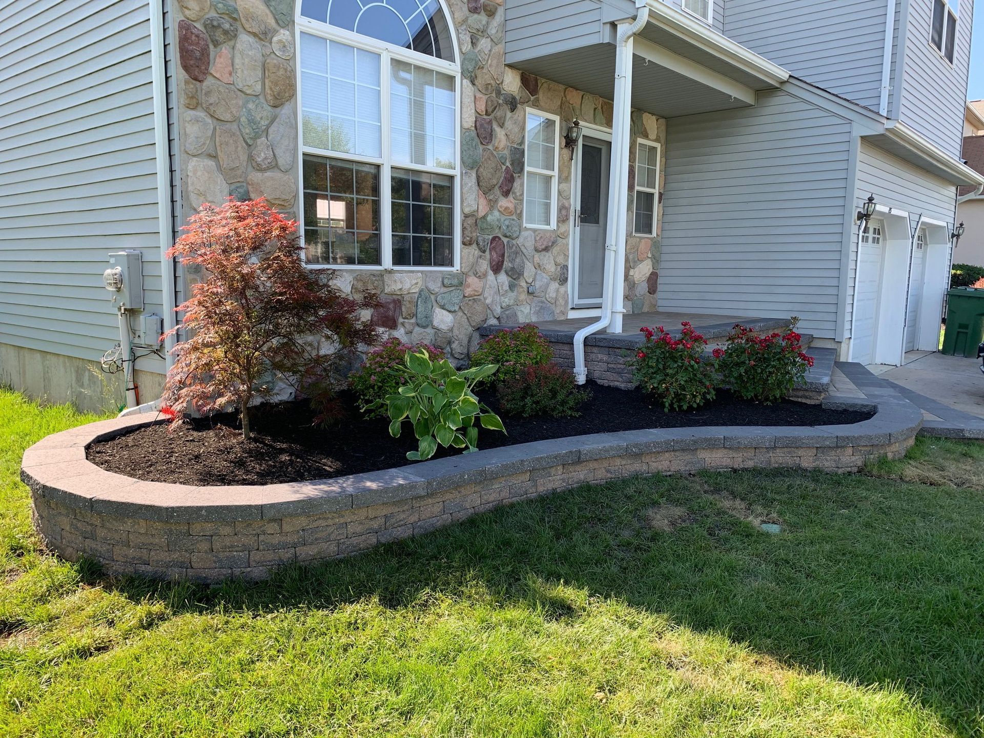 A house with a lush green lawn and a planter in front of it.