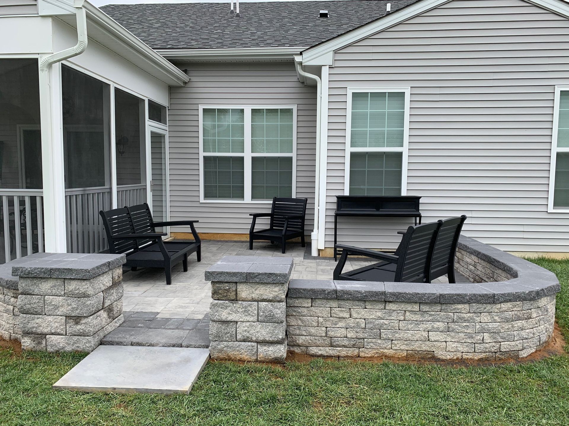 A patio with chairs and a grill in front of a house.