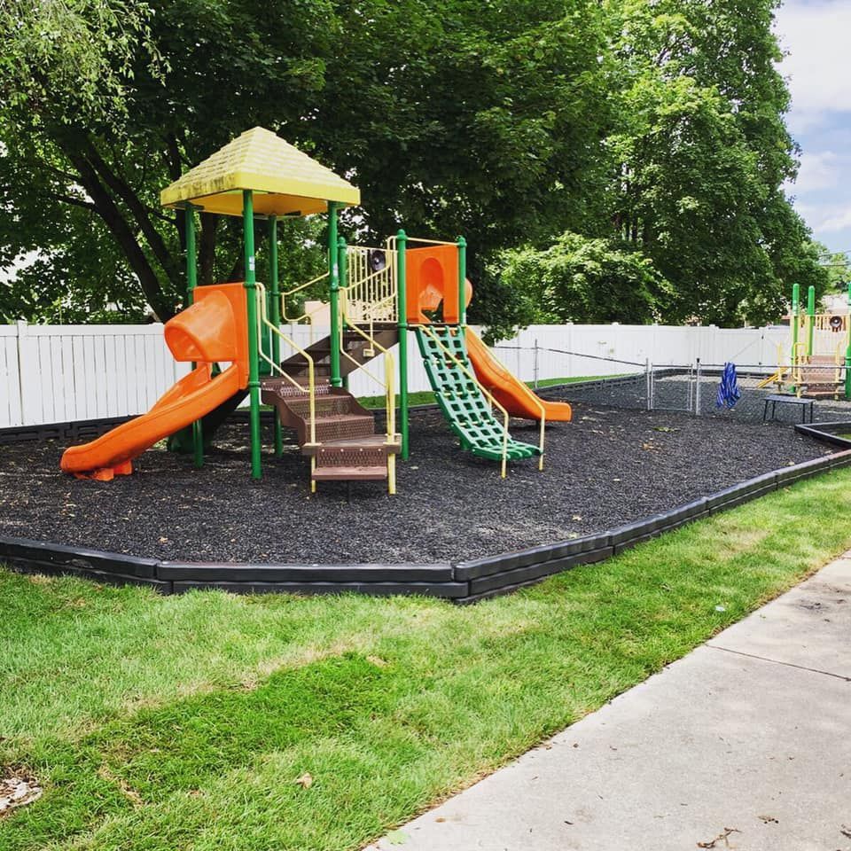 A playground with an orange slide and a yellow canopy