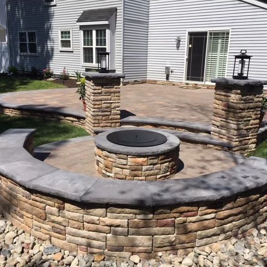 A fire pit is in the middle of a brick wall in front of a house.