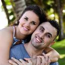 A man is carrying a woman on his back and they are smiling for the camera.