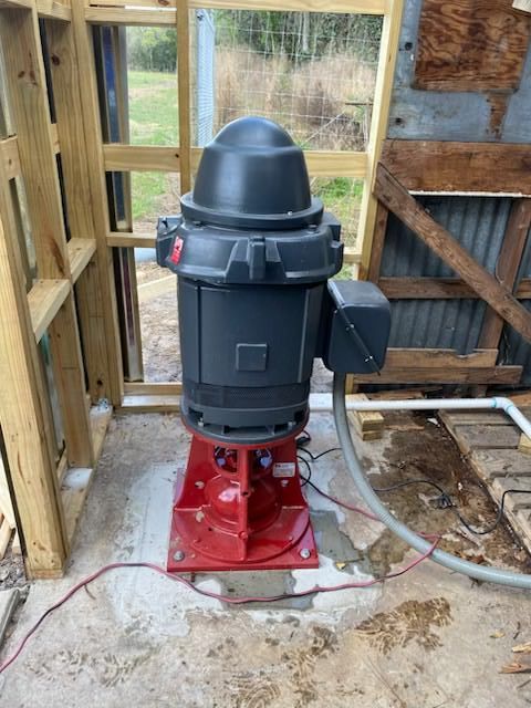 Person in blue shirt holding HVAC gauges with red, yellow, and black hoses.