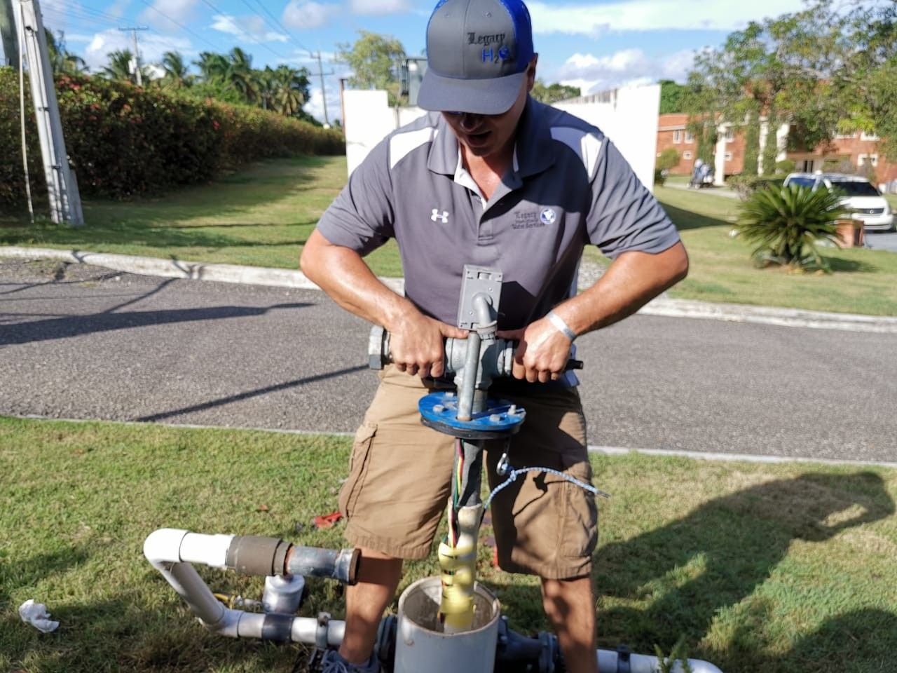 Person in blue shirt holding HVAC gauges with red, yellow, and black hoses.