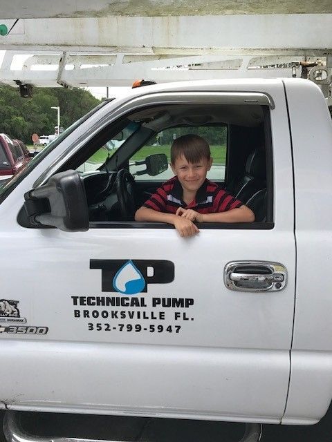 Person in blue shirt holding HVAC gauges with red, yellow, and black hoses.