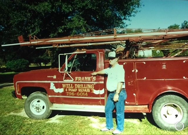 Person in blue shirt holding HVAC gauges with red, yellow, and black hoses.