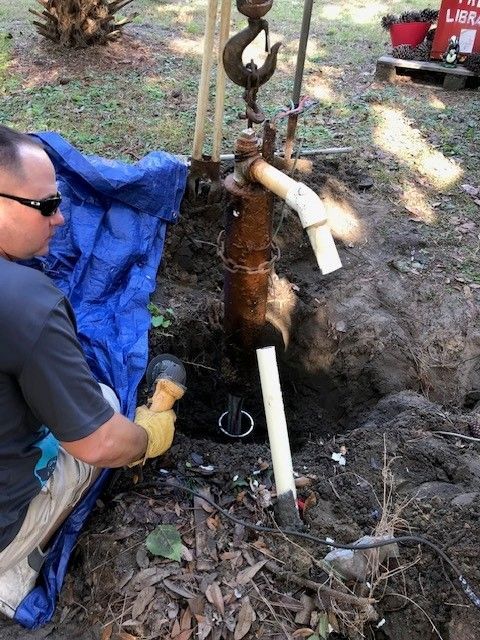 Person in blue shirt holding HVAC gauges with red, yellow, and black hoses.