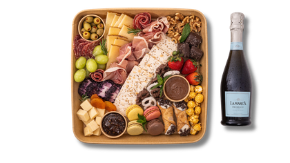 There is a bottle of champagne next to a tray of food.