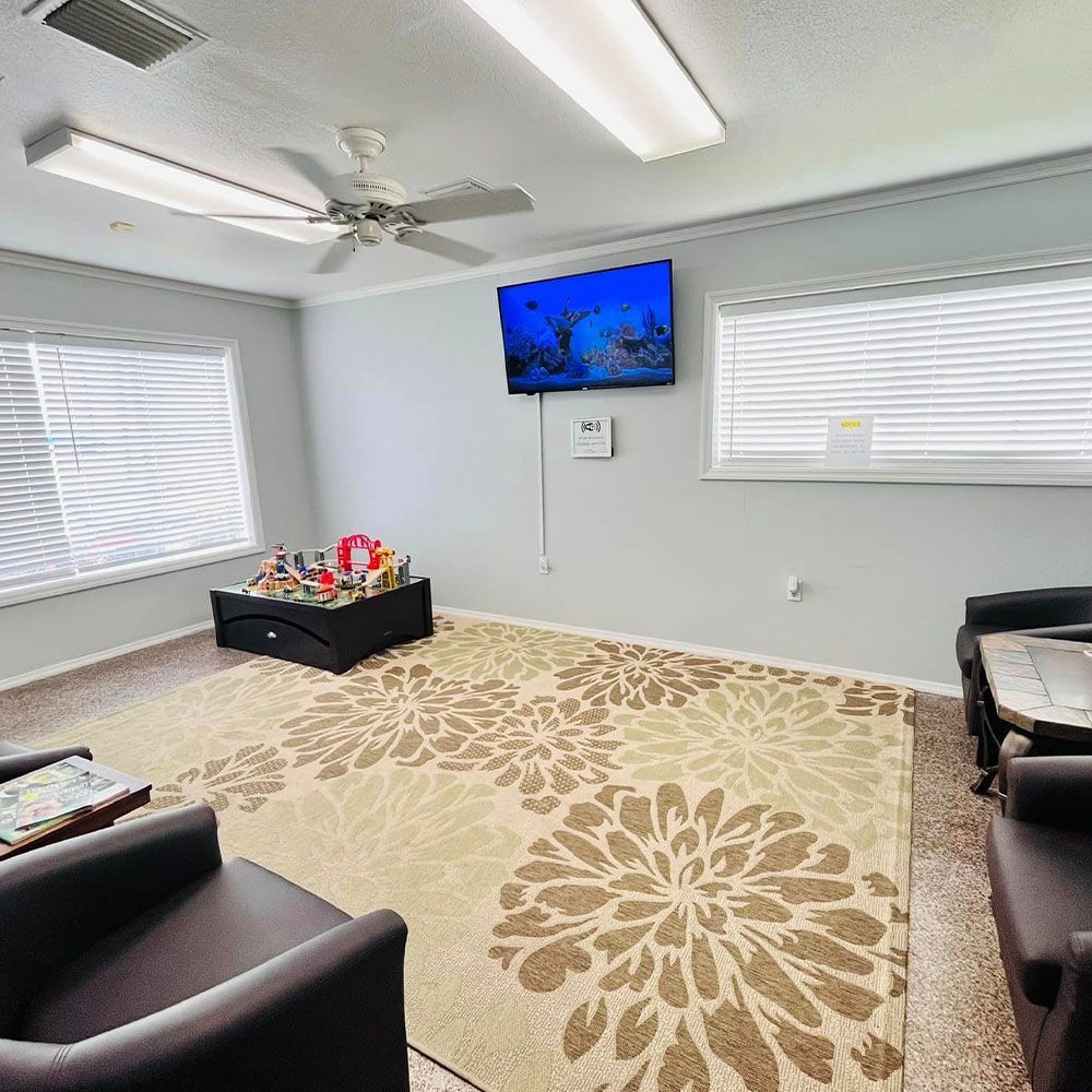 A living room with a rug , chairs , a table and a television.