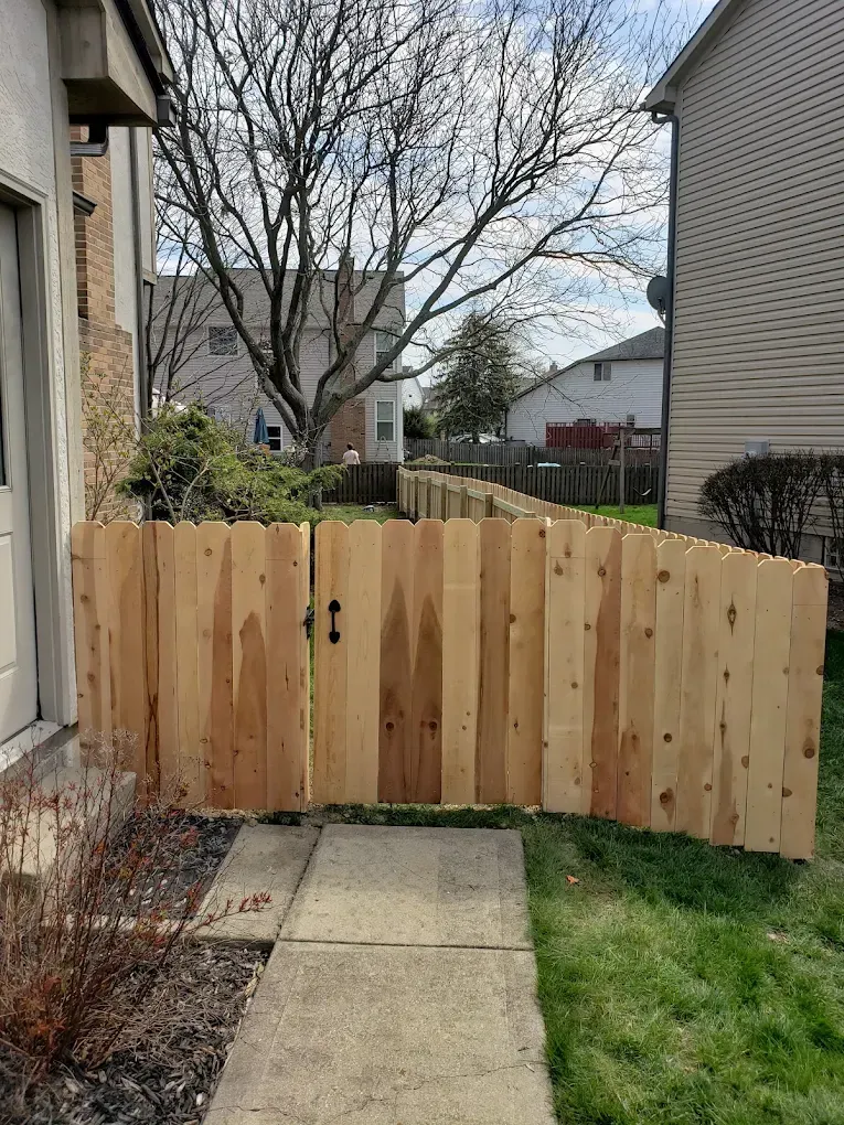 A wooden fence with a gate in front of a house.