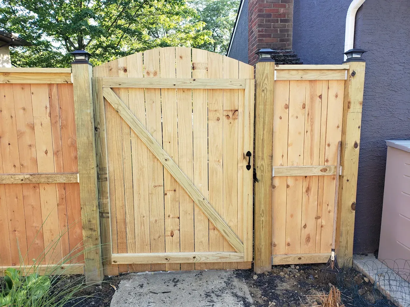A wooden fence with a wooden gate in front of a house.