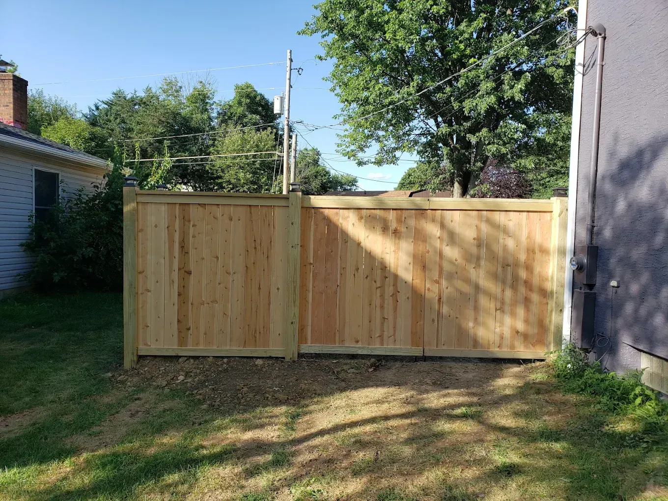 A wooden fence is in the backyard of a house.