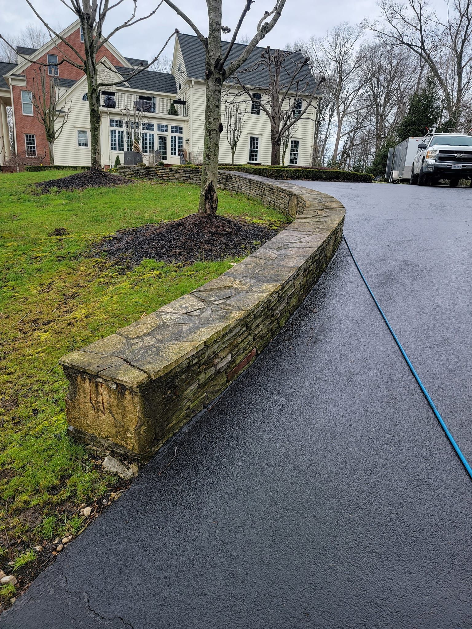 A car is parked on the side of a road next to a stone wall.