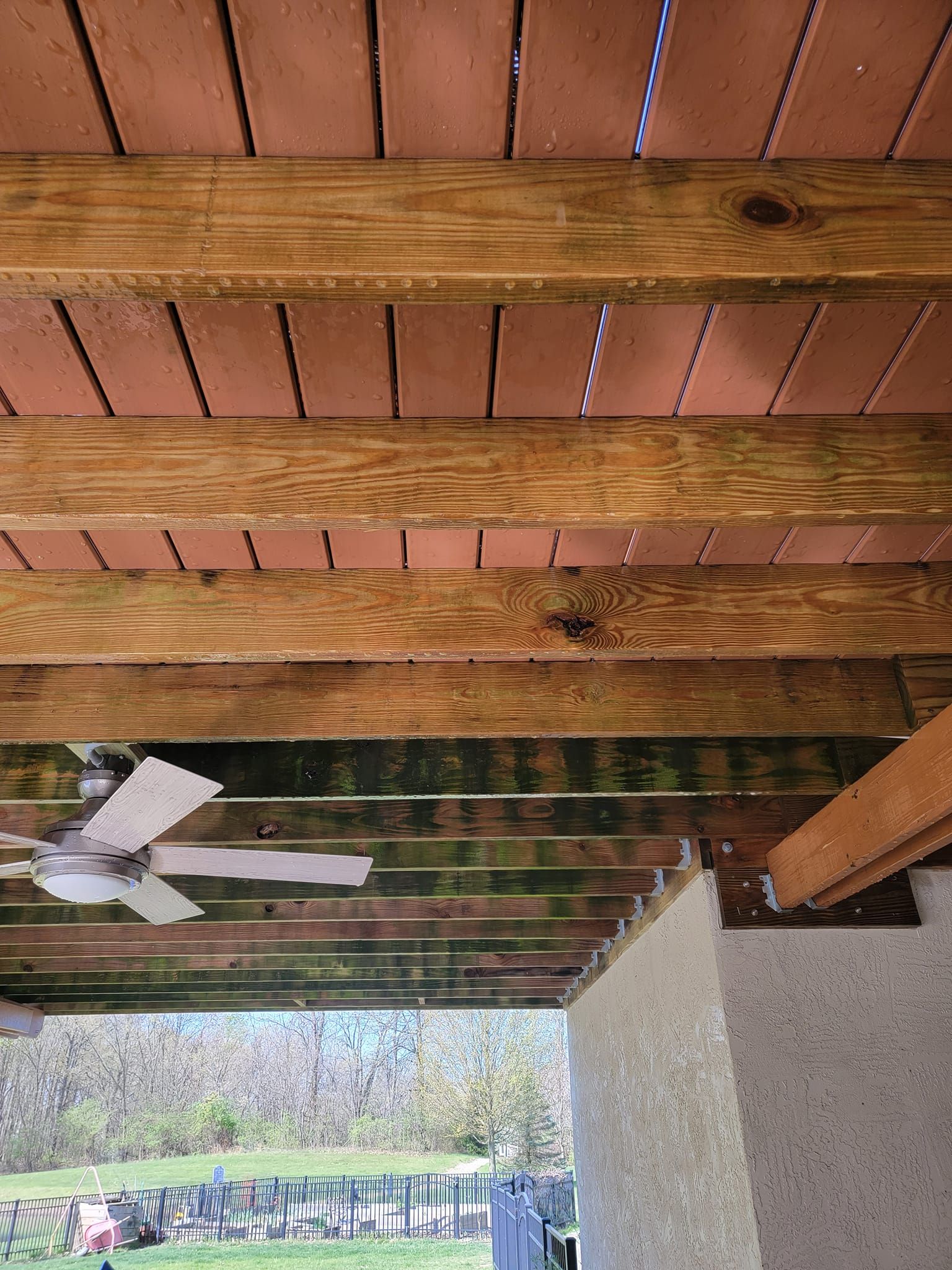 A ceiling fan is hanging from the ceiling of a wooden deck.