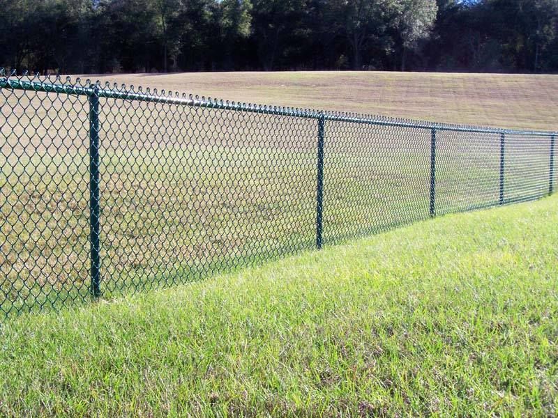 A chain link fence surrounds a grassy field.