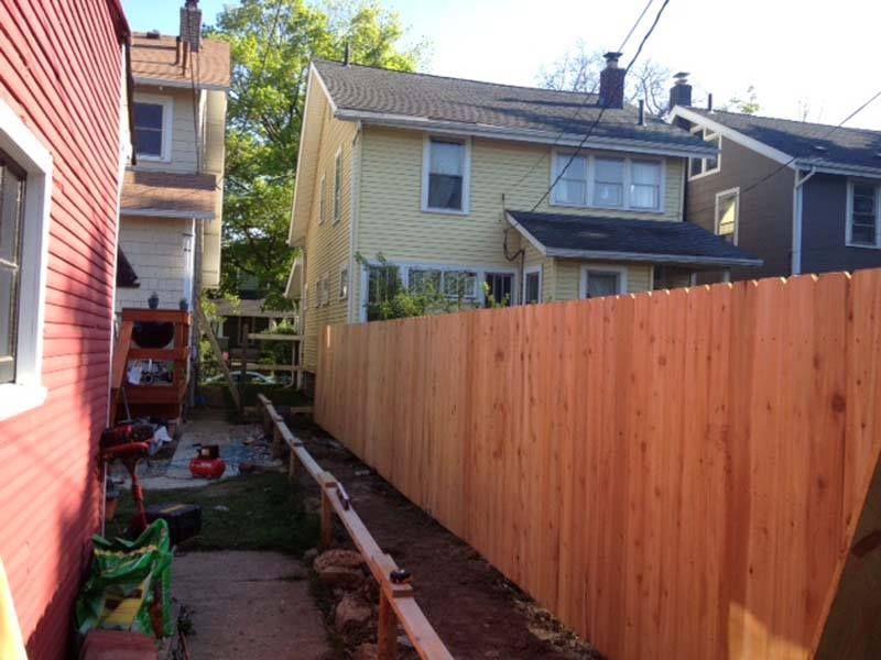A wooden fence is being built in the backyard of a house.