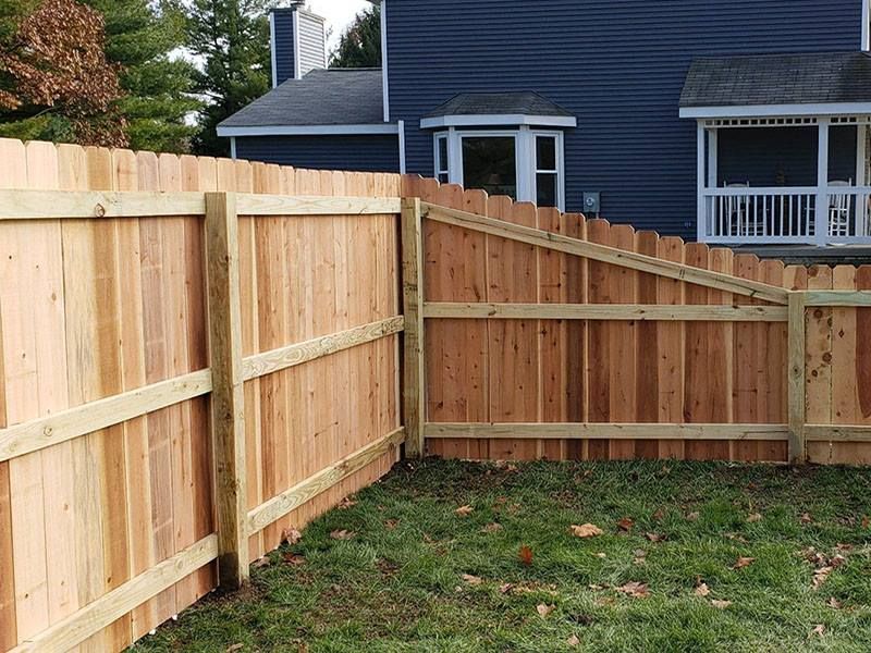 A wooden fence is in the backyard of a house.