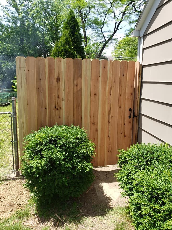 A wooden fence with a gate in the backyard next to a house.