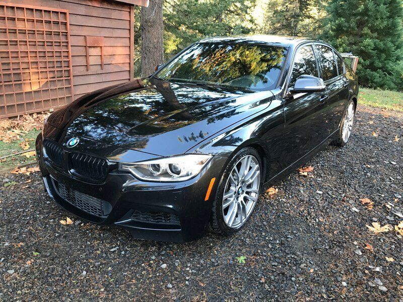 A black bmw is  in front of a wooden building getting a mobile detailing by keptcar