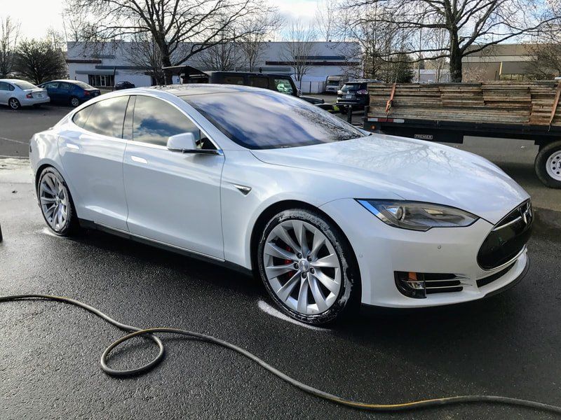 A white tesla model s is parked in a parking lot getting a car wash by keptcar in salem