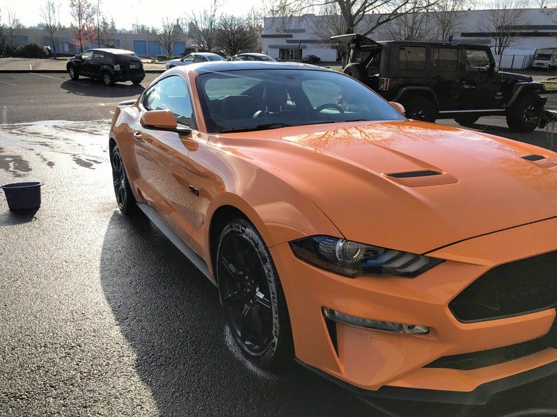 An orange ford mustang is getting detailed  at work  in  salem oregon