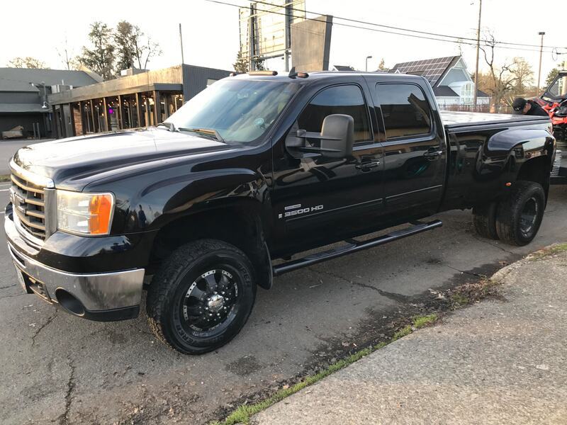 A black pickup truck is parked on the side of the road getting a detail by keptcar