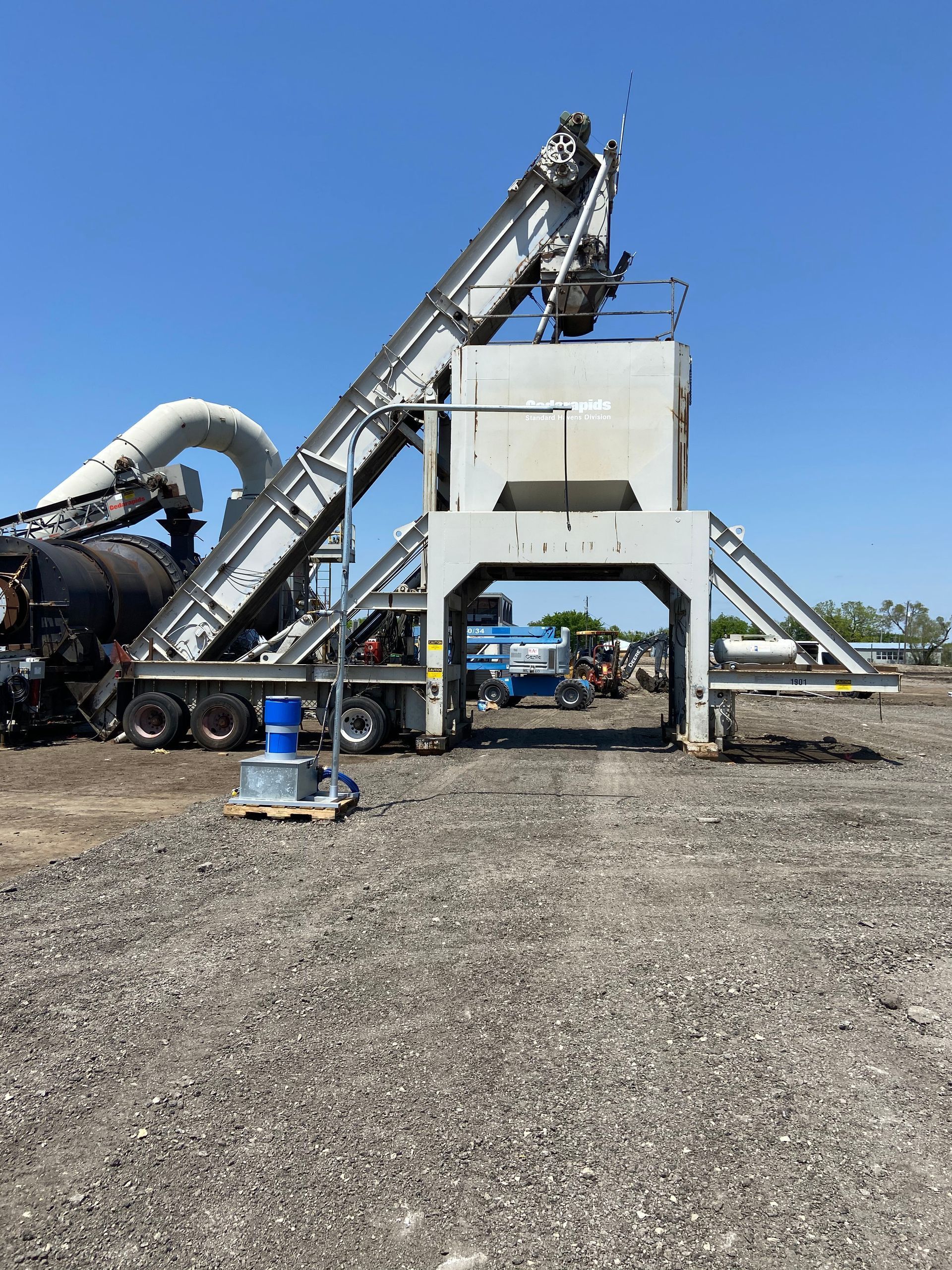 A large machine is sitting in the middle of a gravel field.