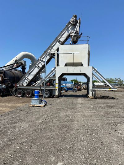 A large machine is sitting in the middle of a gravel field.