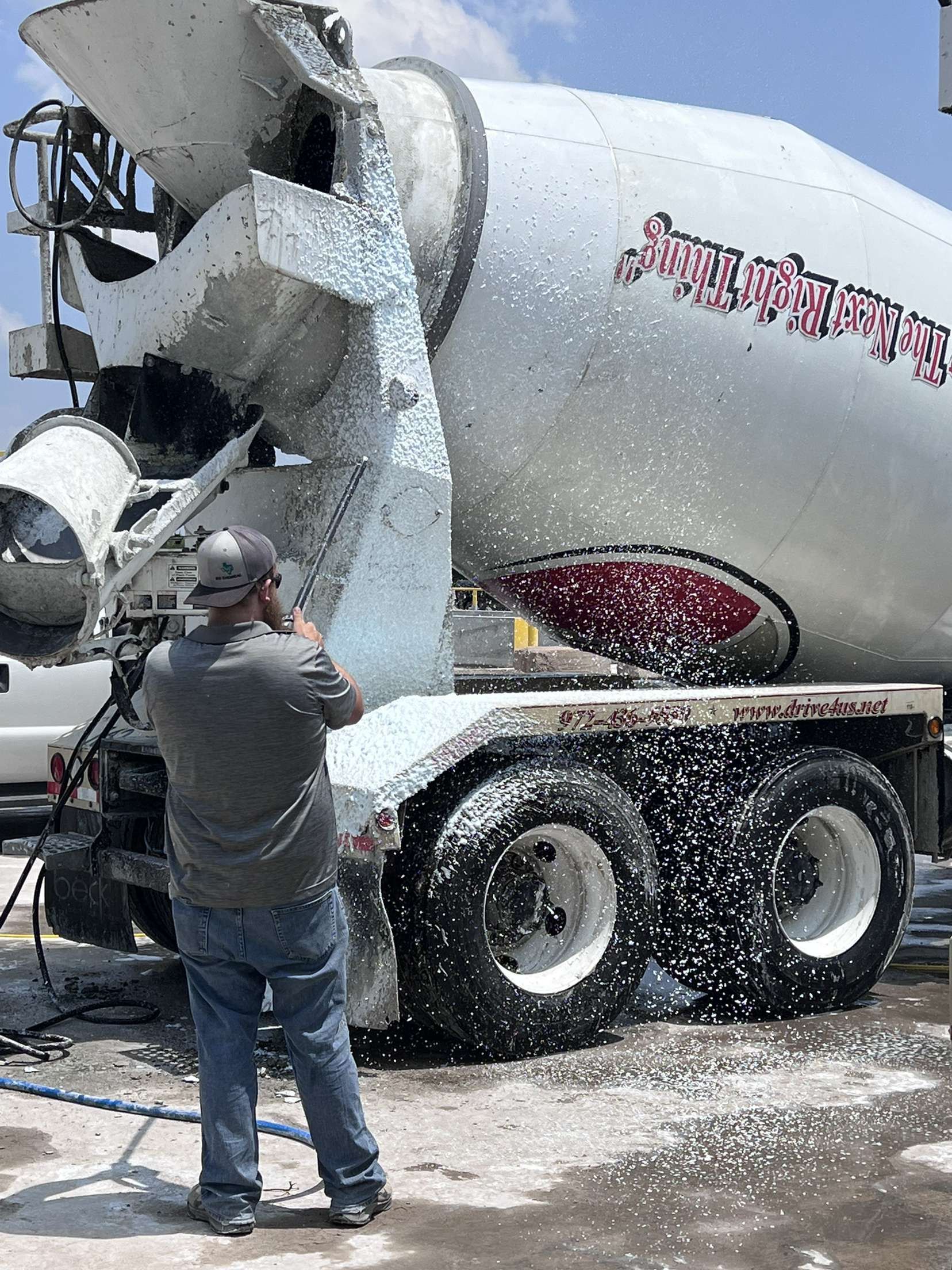 A man is standing in front of a concrete mixer truck.