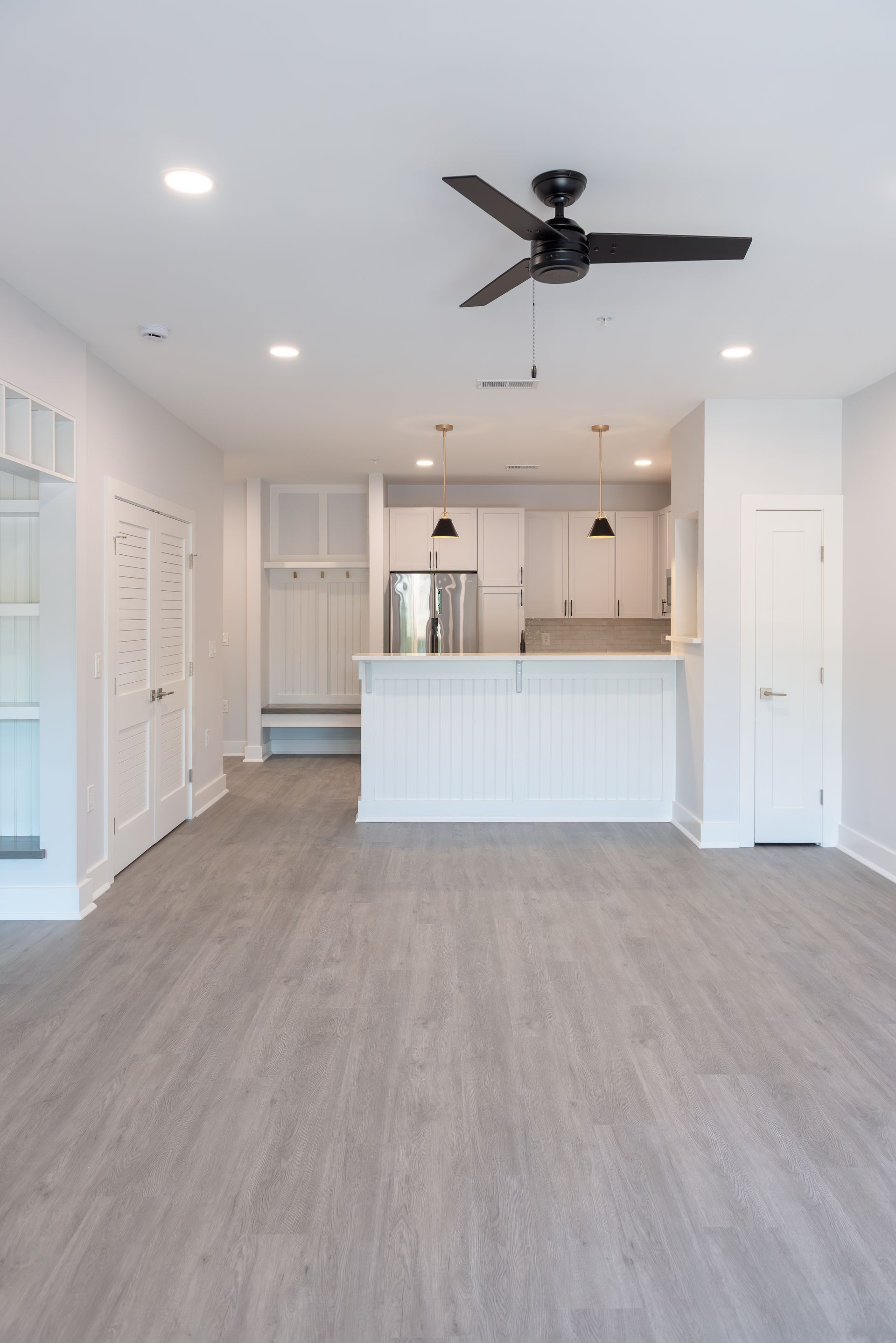 Open concept living space with gray flooring, white walls, and a kitchen with a white island.