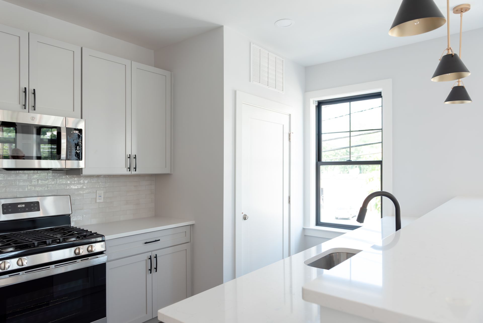 Modern kitchen with white cabinets, stainless steel appliances, and black accents.