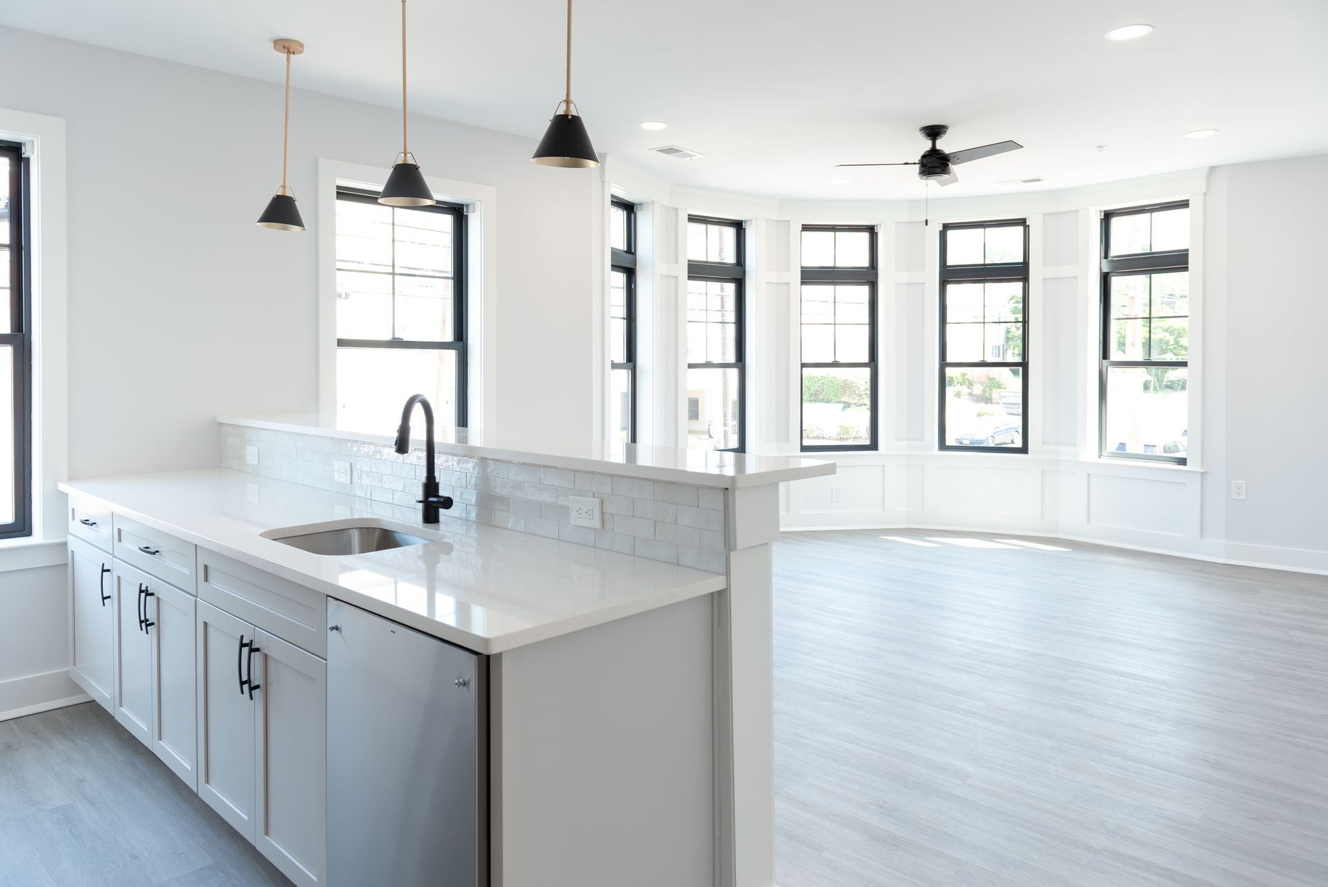 Modern kitchen with white cabinets, marble countertop, and a bay window.
