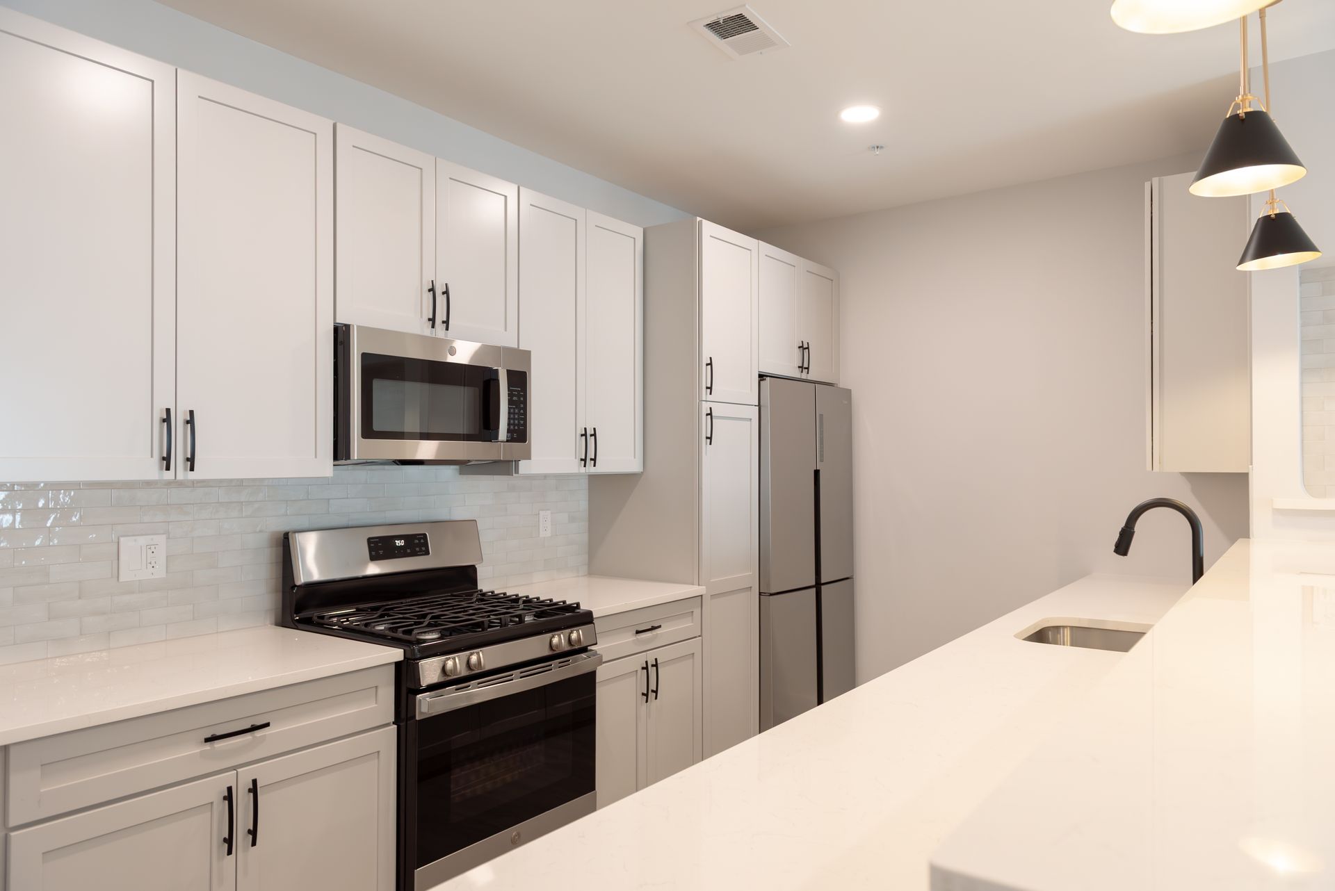White kitchen with stainless steel appliances and white countertops.