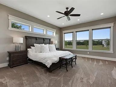Bedroom with dark wooden furniture, white bedding, and large windows overlooking a green landscape.