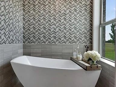 Bathroom with a white freestanding tub, herringbone tile, and window with a countryside view.